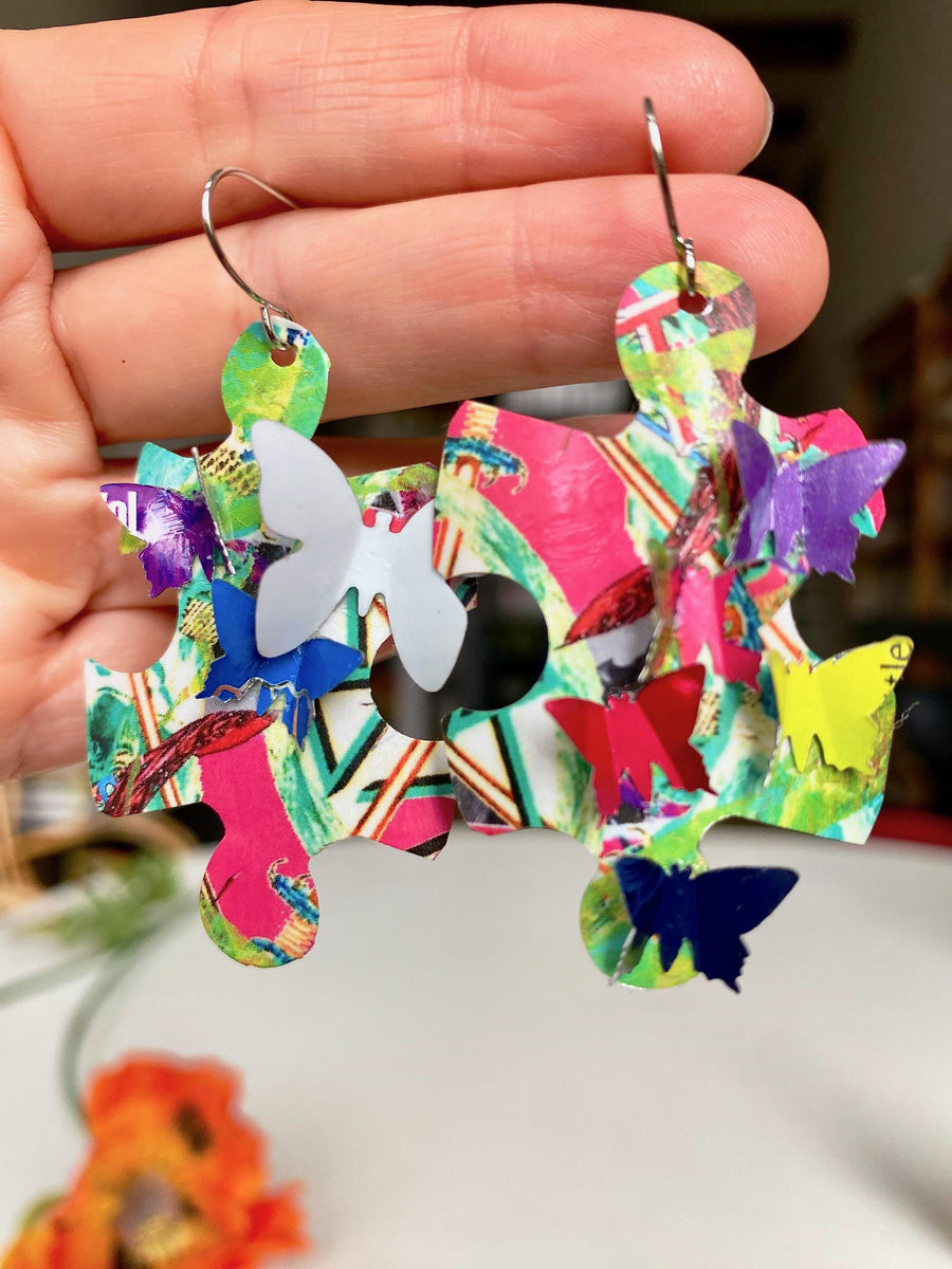 multicoloured, bright puzzle shaped earrings with butterflies made from craft beer cans by laura zabo hang in hand