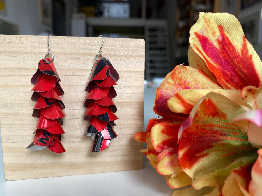 red cascade earrings made from upcycled coca cola aluminum canson a wooden background and flower decoration