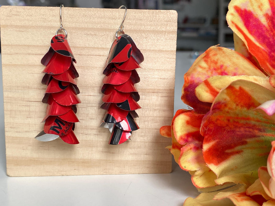 red cascade earrings made from upcycled coca cola aluminum canson a wooden background and flower decoration