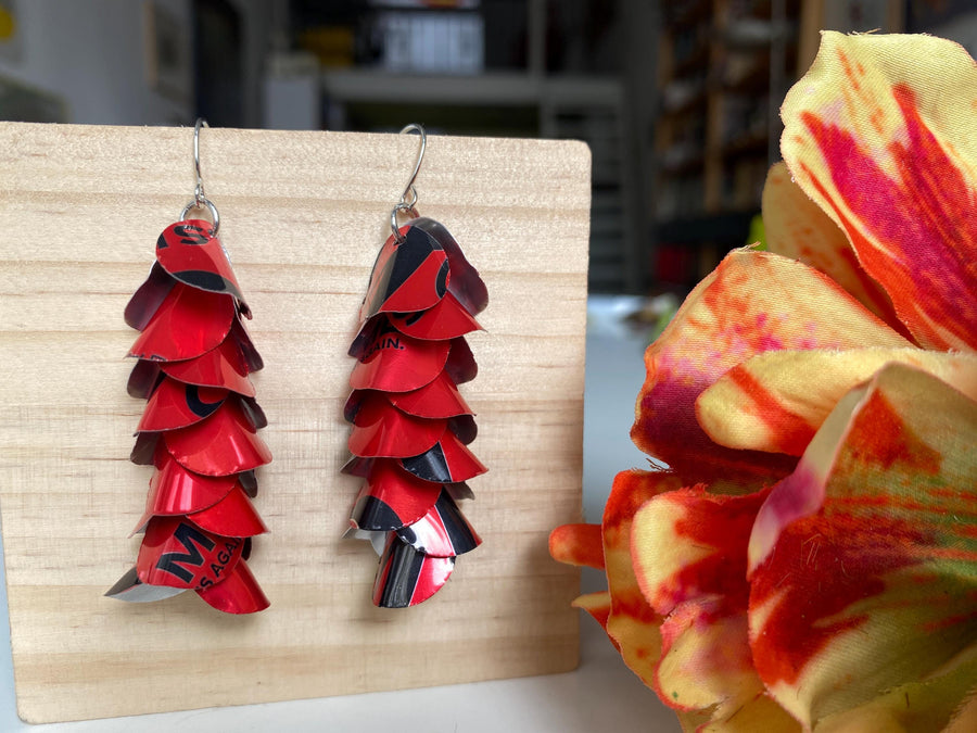red cascade earrings made from upcycled coca cola aluminum canson a wooden background and flower decoration