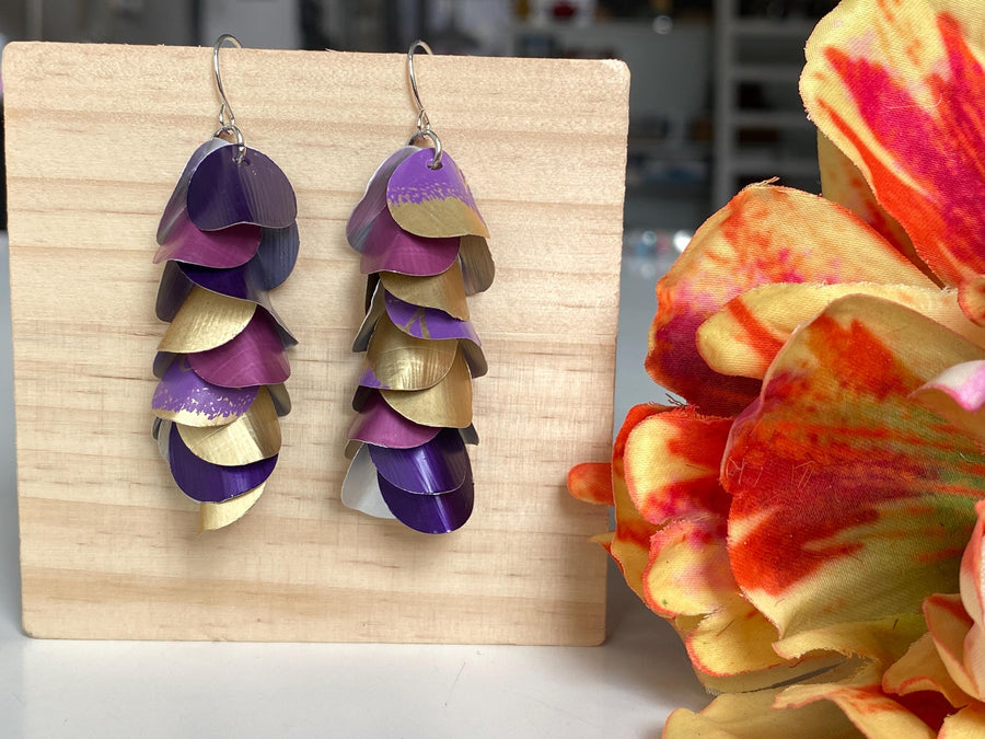 gold purple cascade earrings made from upcycled nespresso pods by Laura zabo on a wooden background and a flower