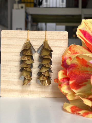 dark gold cascade earrings made from upcycled nespresso coffee pods, Nicaragua capsules by laura zabo, on a wooden background and flower decoration