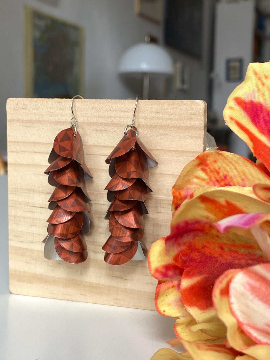 rust-copper coloured cascade earrings made from Nespresso Cape Town Lungo Capsules by Laura Zabo on a wooden background and flower decoration