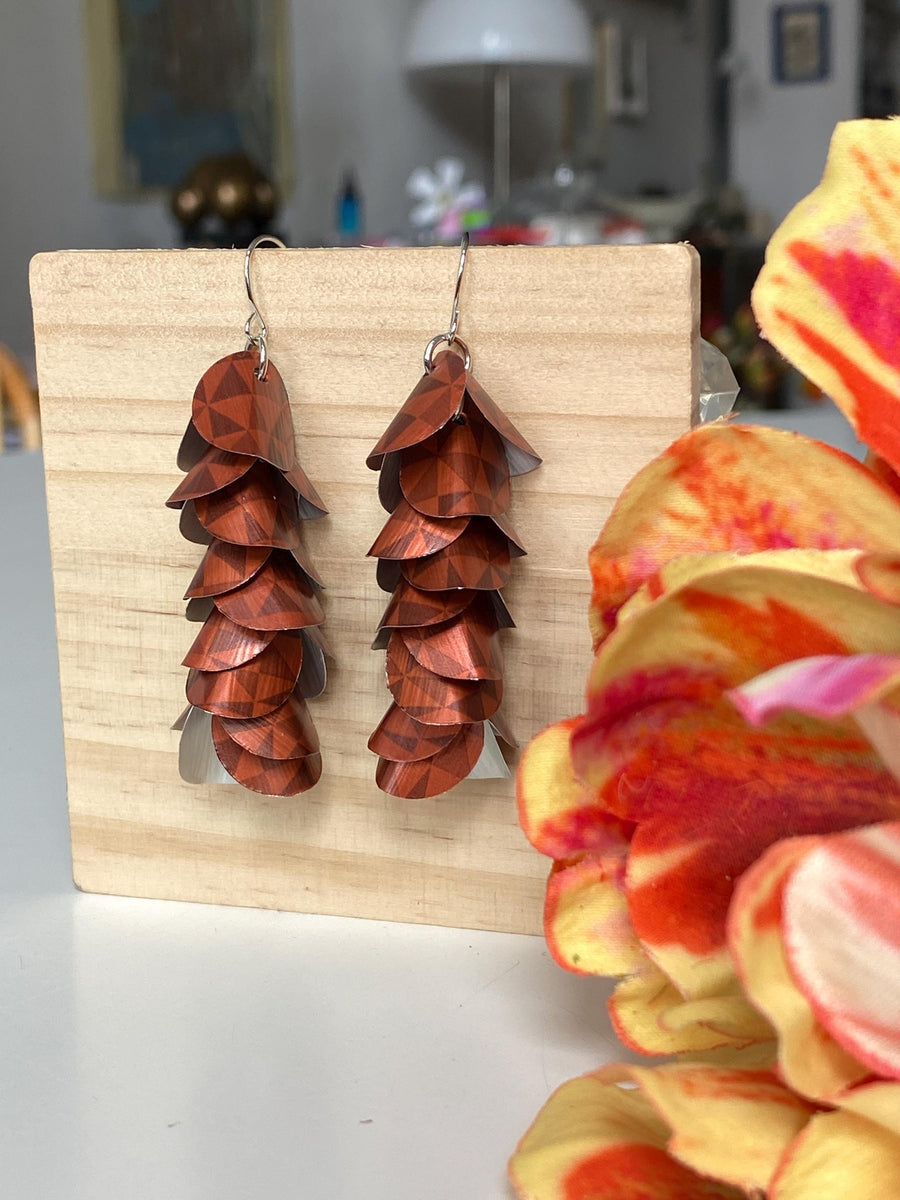 rust-copper coloured cascade earrings made from Nespresso Cape Town Lungo Capsules by Laura Zabo on a wooden background and flower decoration