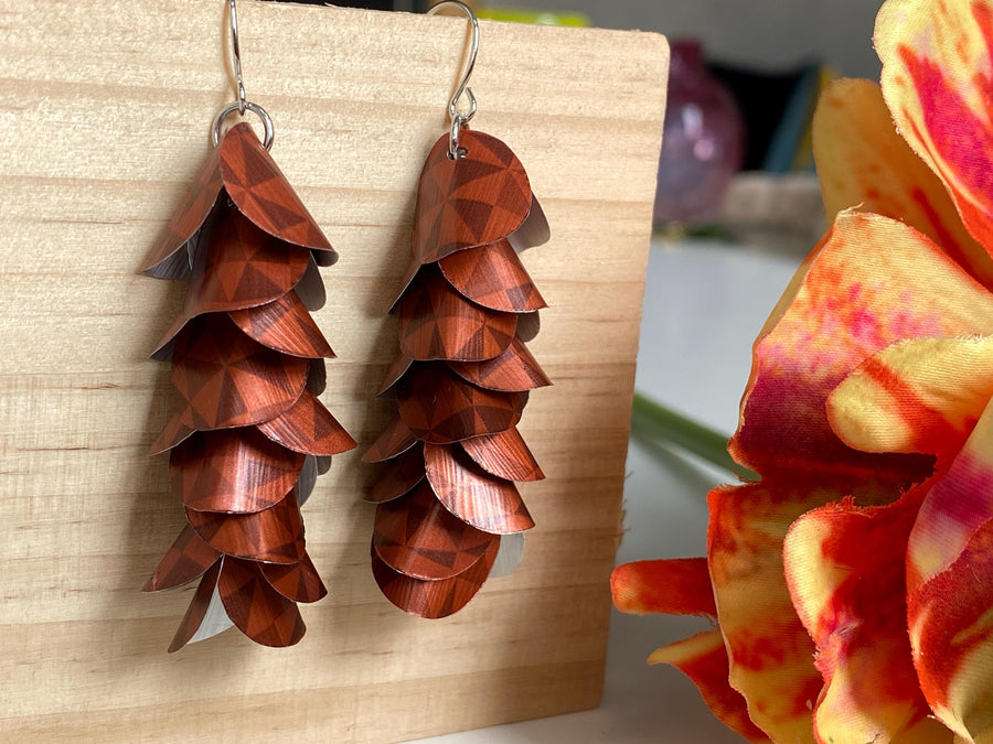 rust-copper coloured cascade earrings made from Nespresso Cape Town Lungo Capsules by Laura Zabo on a wooden background and flower decoration