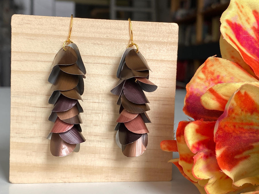 brown coloured cascade earrings made from upcycled nespresso capsules by Laura Zabo, on a wooden background a flower decoration