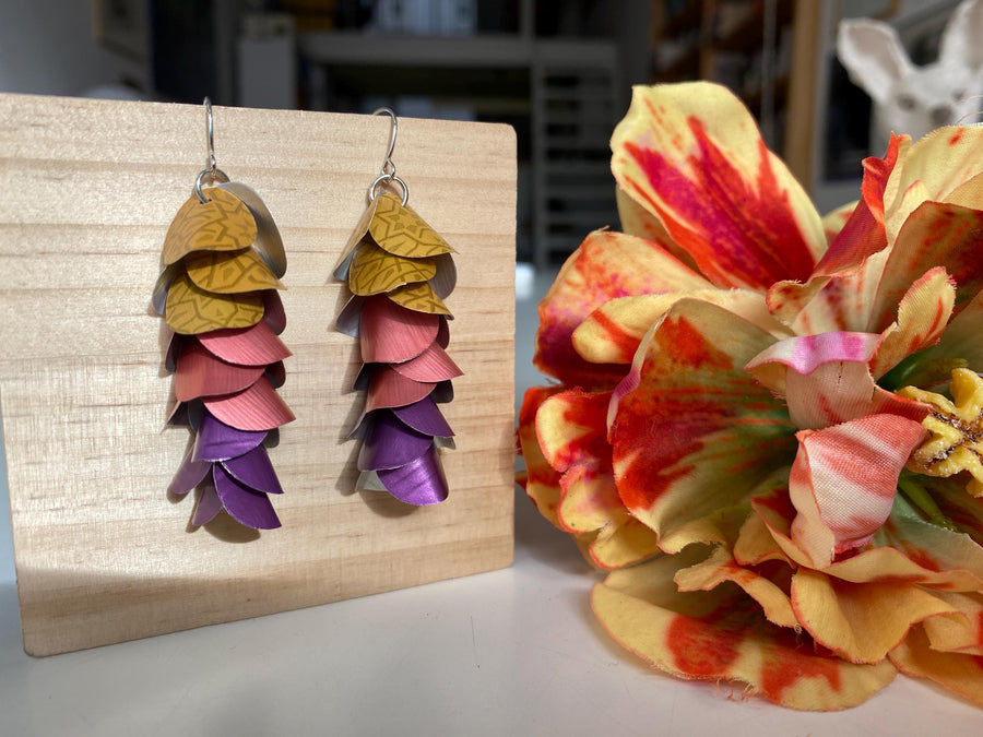 mustard peach and purple coloured cascade earrings made from repurposed nespresso coffee pods by Laura Zabo on a wooden background and flower decoration