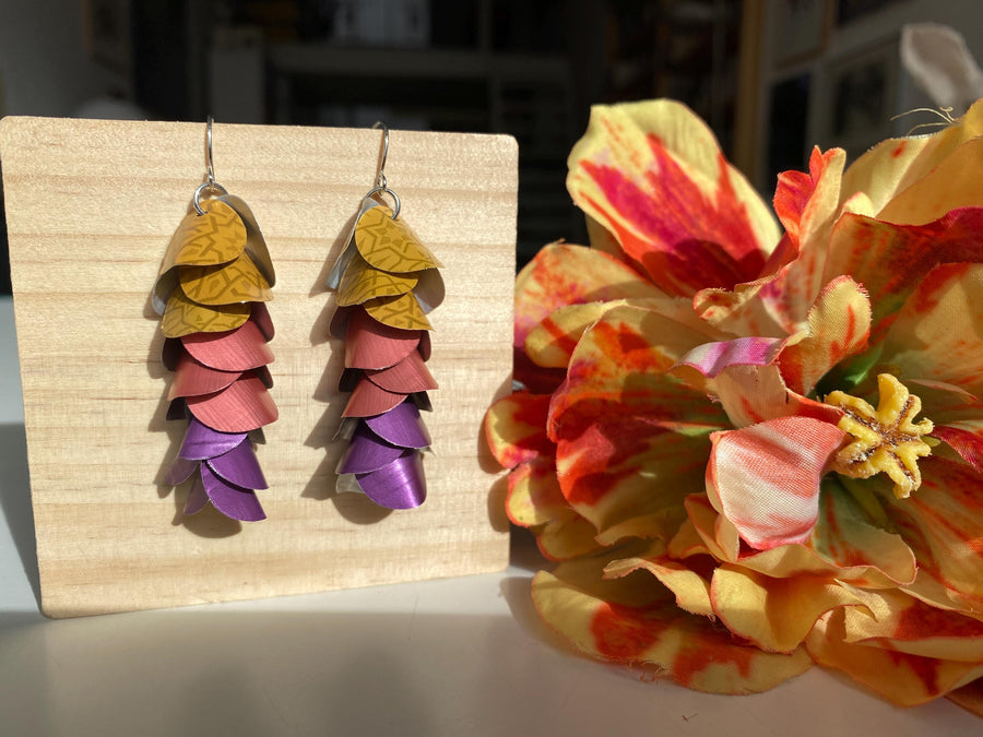 mustard peach and purple coloured cascade earrings made from repurposed nespresso coffee pods by Laura Zabo on a wooden background and flower decoration