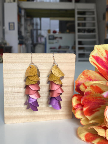 mustard peach and purple coloured cascade earrings made from repurposed nespresso coffee pods by Laura Zabo on a wooden background and flower decoration