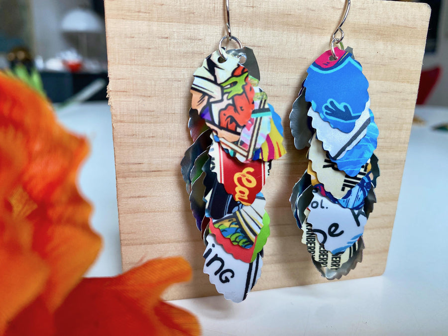 colorful, bright, graffiti style cascade earrings made from upcycled craft beer can by laura zabo on a wooden background and flower decoration