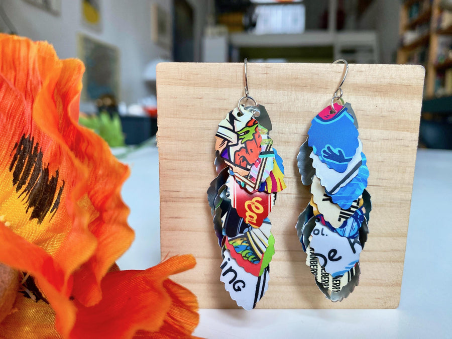 colorful, bright, graffiti style cascade earrings made from upcycled craft beer can by laura zabo on a wooden background and flower decoration