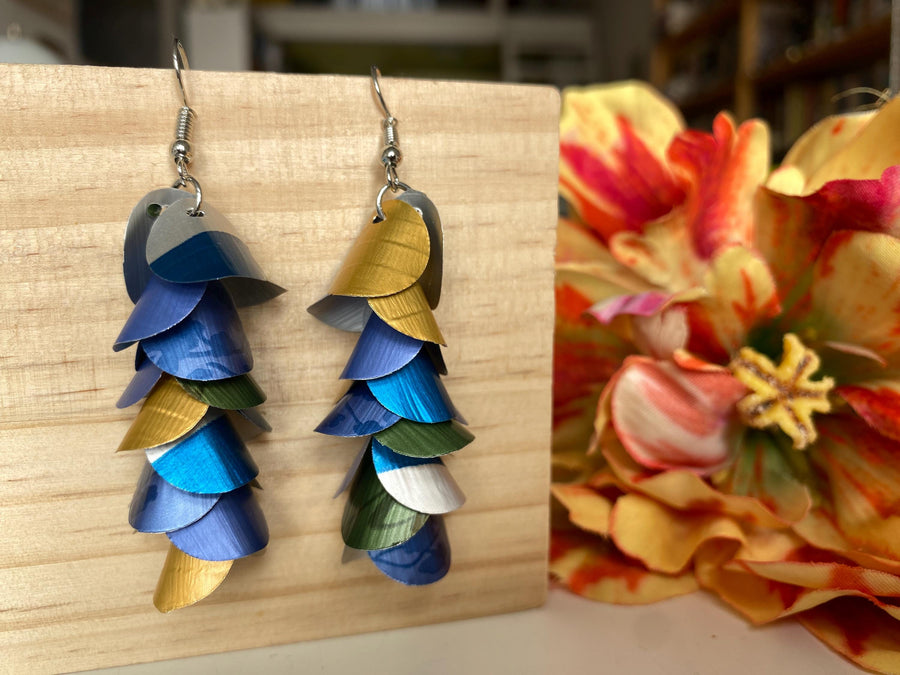 blue green gold silver cascade earrings made from upcycled nespresso capsules by laura zabo on a wooden background and flower decoration