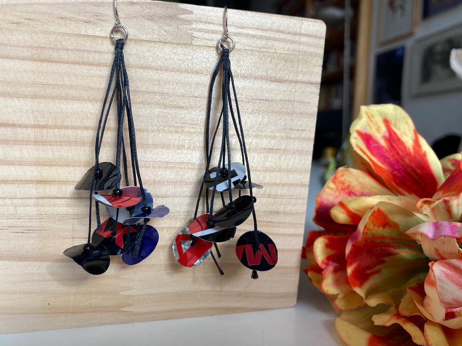 black blue red earrings on waxed cotton made from upcycled pepsi cans on a wooden background and flower decoration