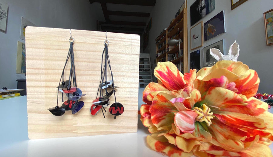 black blue red earrings on waxed cotton made from upcycled pepsi cans on a wooden background and flower decoration