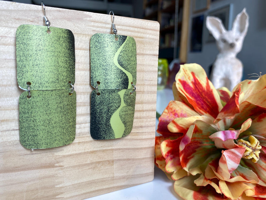 mint green and black retro 90s earrings made from upcycled craft beer can by Laura zabo, on a wooden background and flower decoration