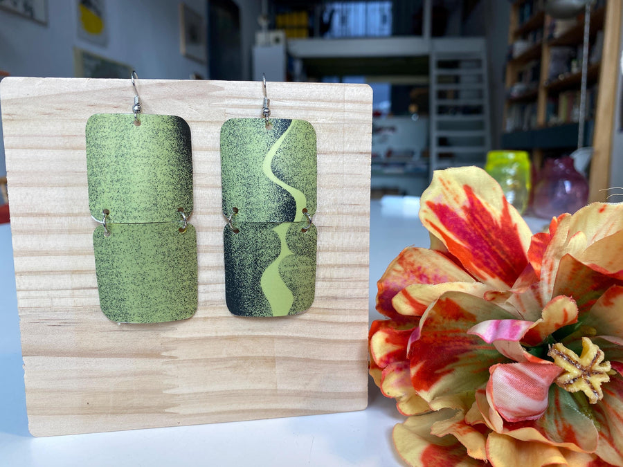 mint green and black retro 90s earrings made from upcycled craft beer can by Laura zabo, on a wooden background and flower decoration