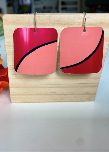 Laura Zabo , dark and light pink squared earrings made from shiny craft beer can, on a wooden background and flower decoration