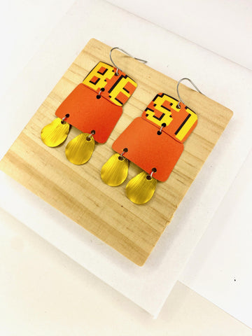 Laura Zabo statement earrings in orange yellow and gold colours, made from upcycled craft beer cans and nespresso capsules on a wooden and white background