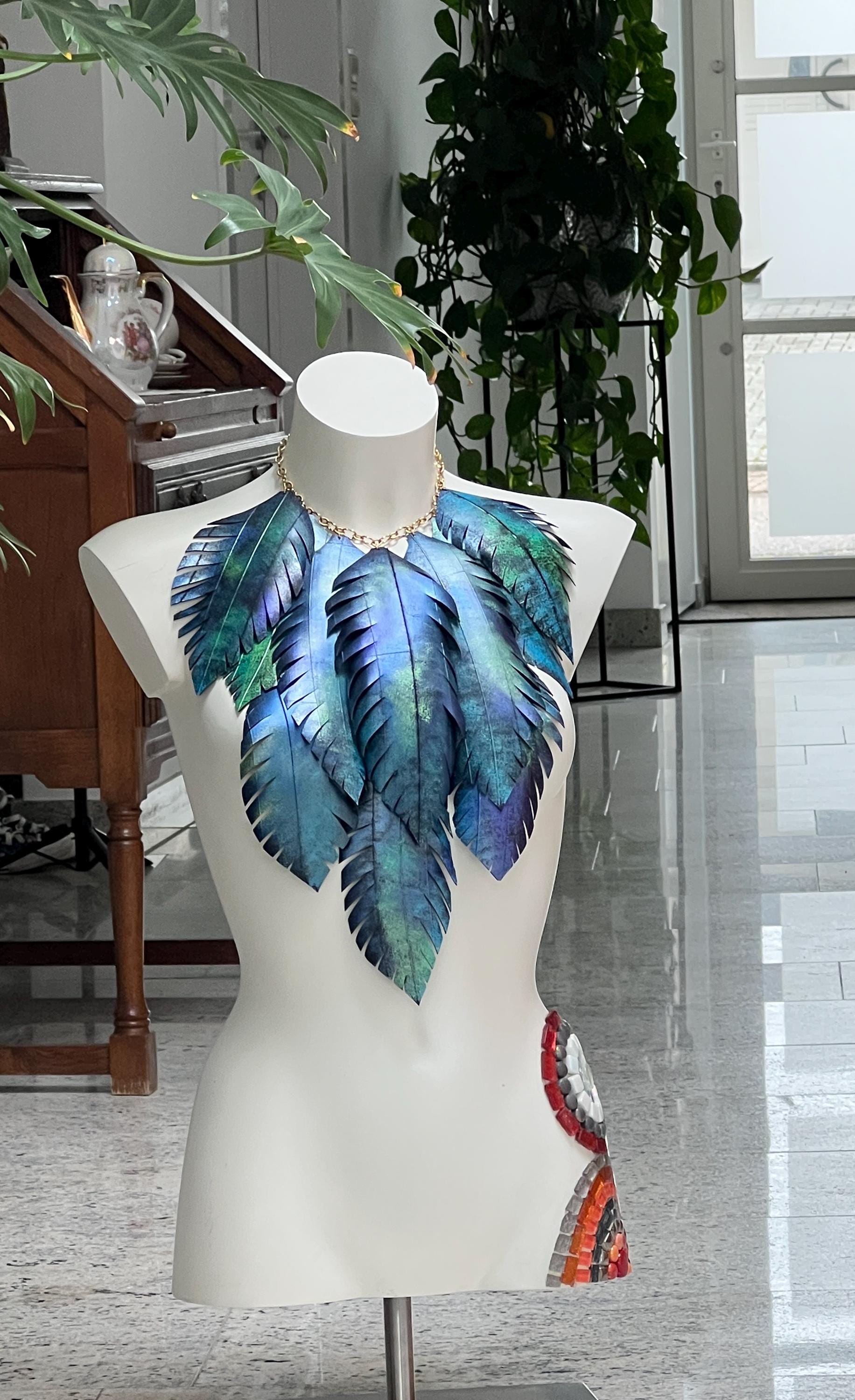 large blue green leaf necklace, neckpiece made from upcycled bicycle innertube rubber on a white mannequin against a cosy room