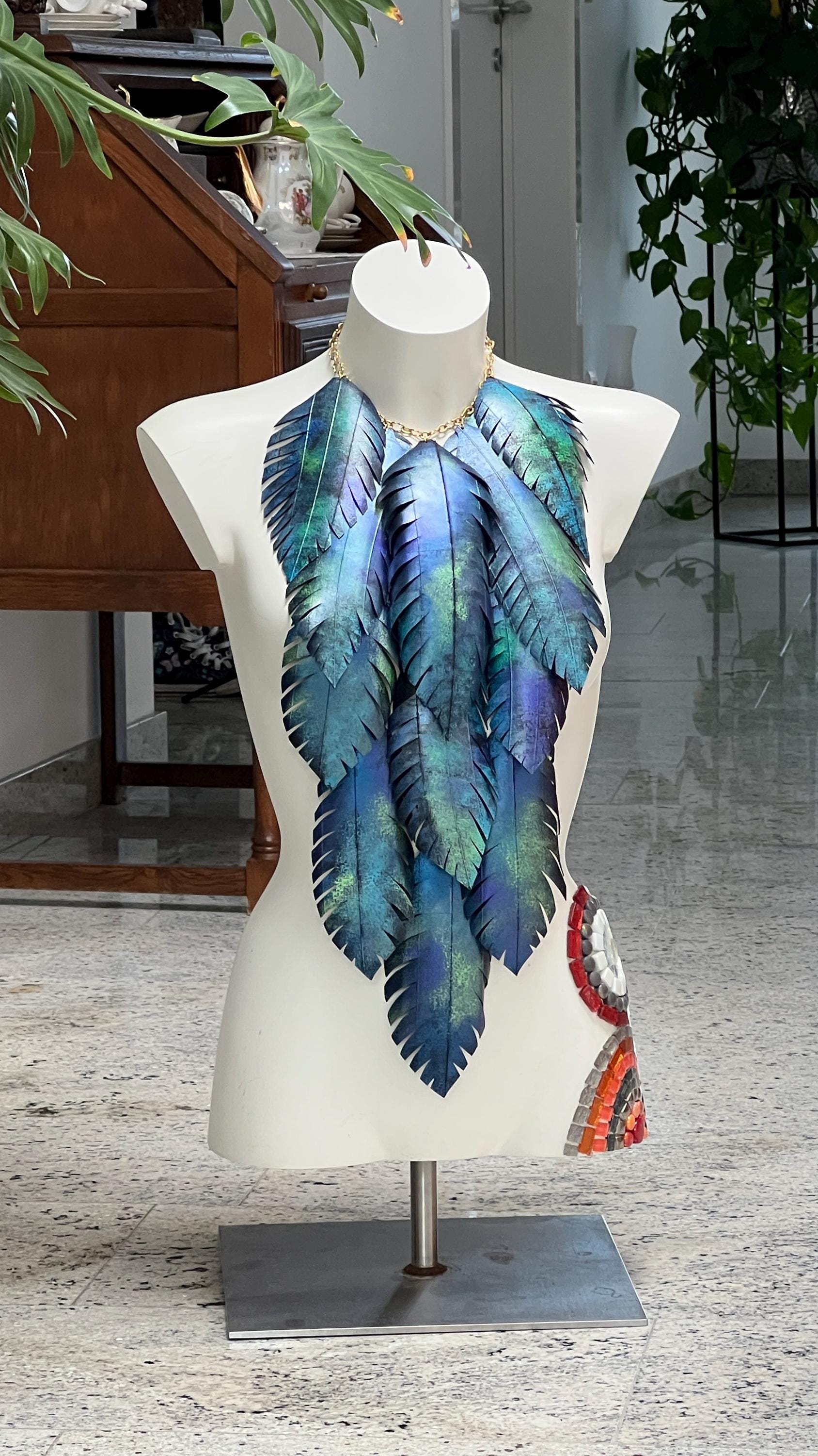 large blue green leaf necklace, neckpiece made from upcycled bicycle innertube rubber on a white mannequin against a cosy room