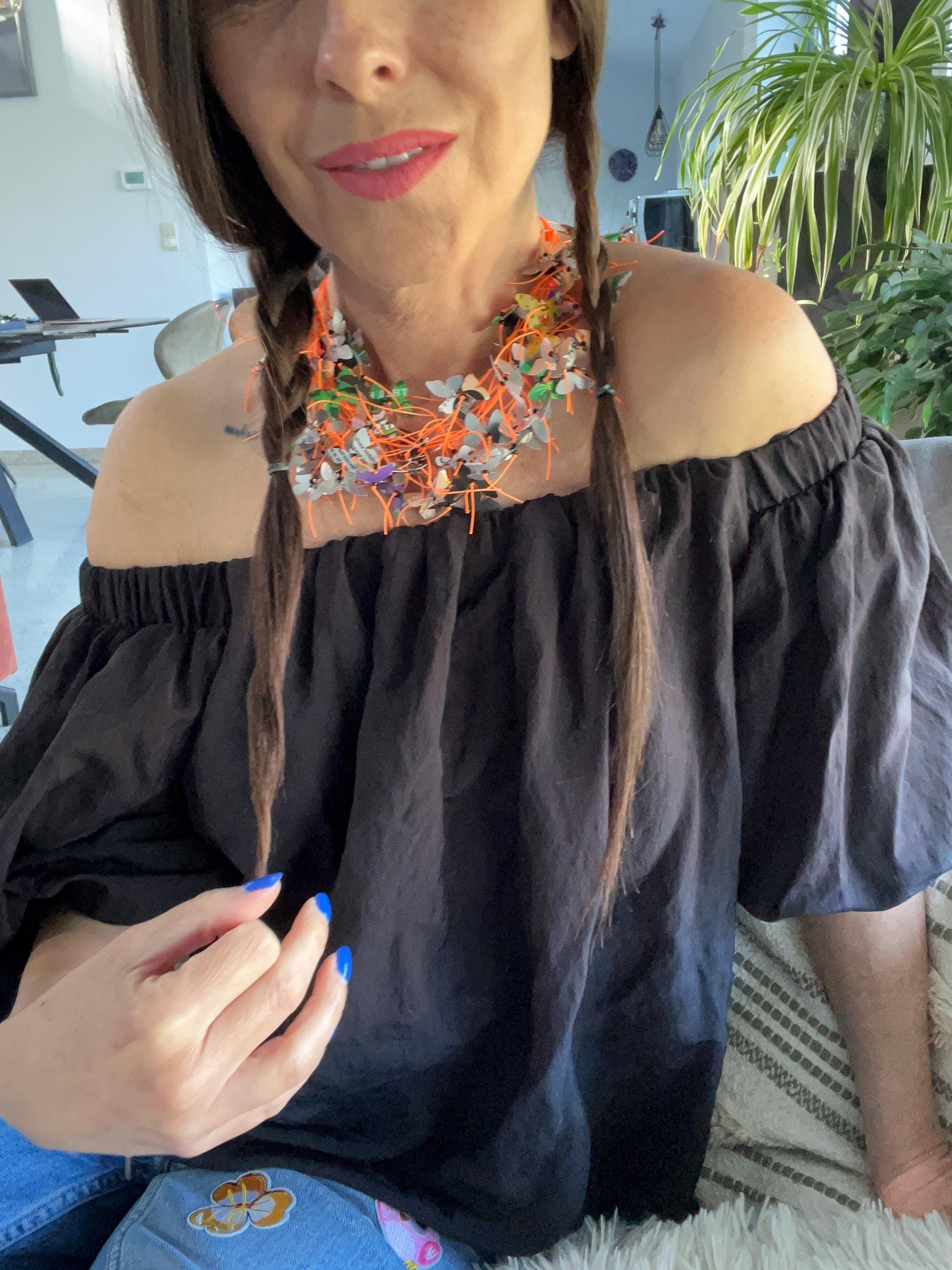 model wears orange cord and aluminium butterfly necklace, the butterflies are cut from upcycled soda and beer cans