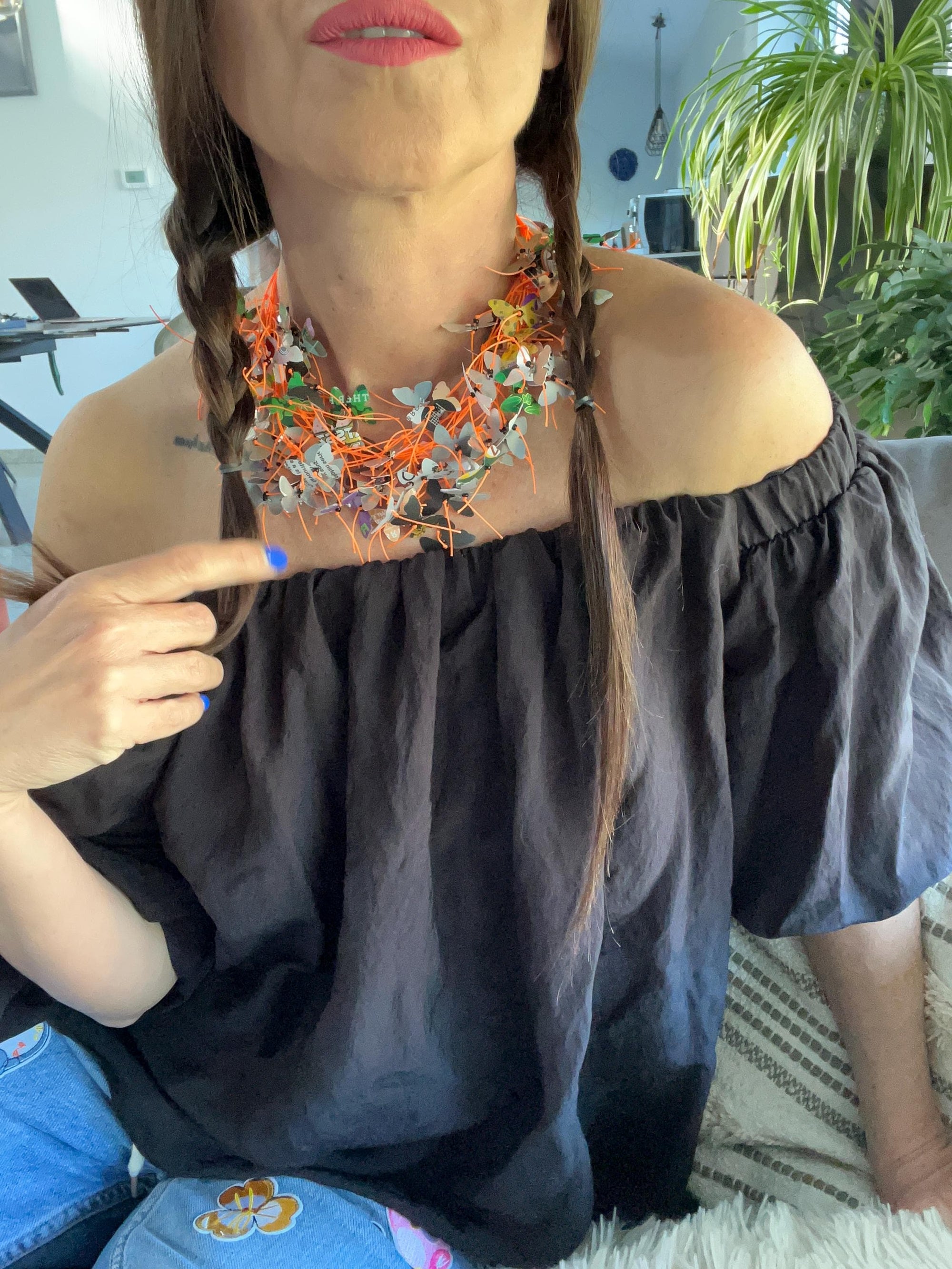 orange cord and aluminium butterfly necklace, the butterflies are cut from upcycled soda and beer cans on a white mannequin