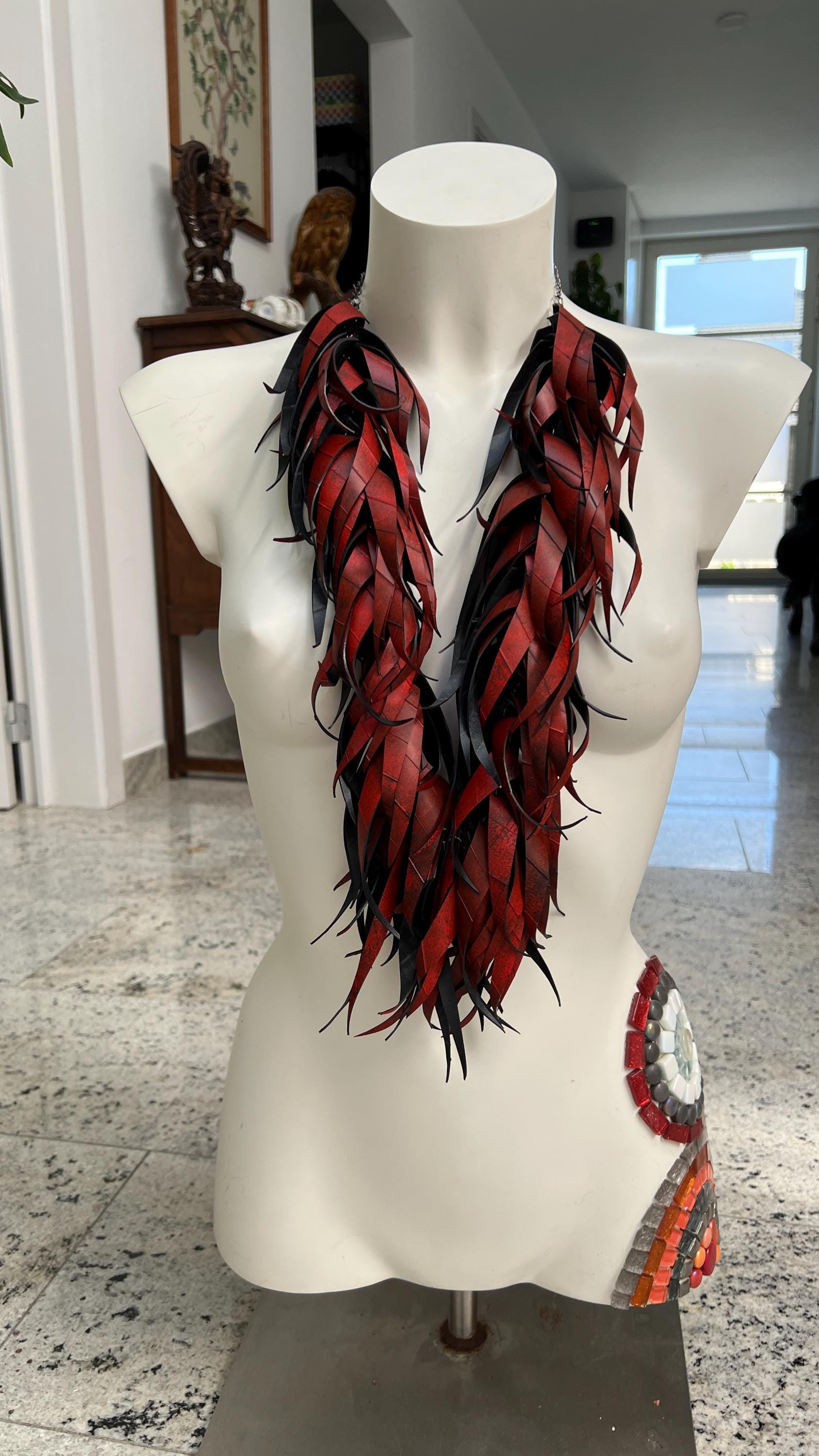 large, long red curly tassel neckace made from upcycled bicycle inner tube rubber on a white mannequin