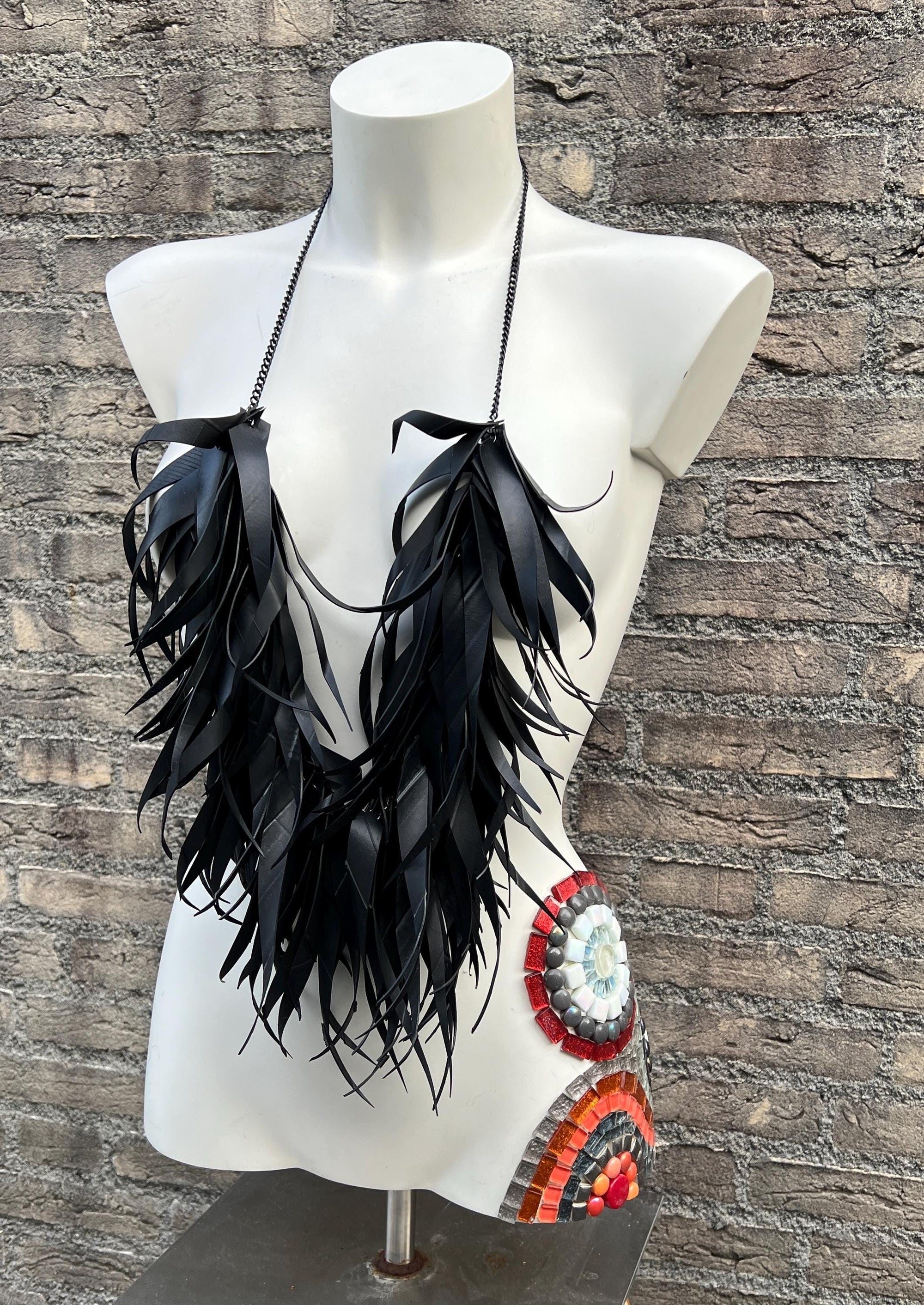 very large, oversized black curly tassel made from upcycled bicycle inner tube tassels on a white mannequin