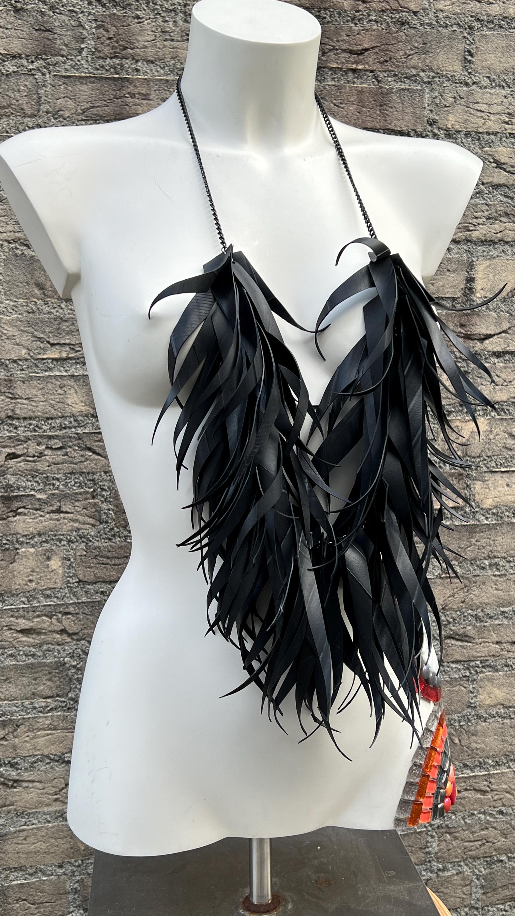 very large, oversized black curly tassel made from upcycled bicycle inner tube tassels on a white mannequin