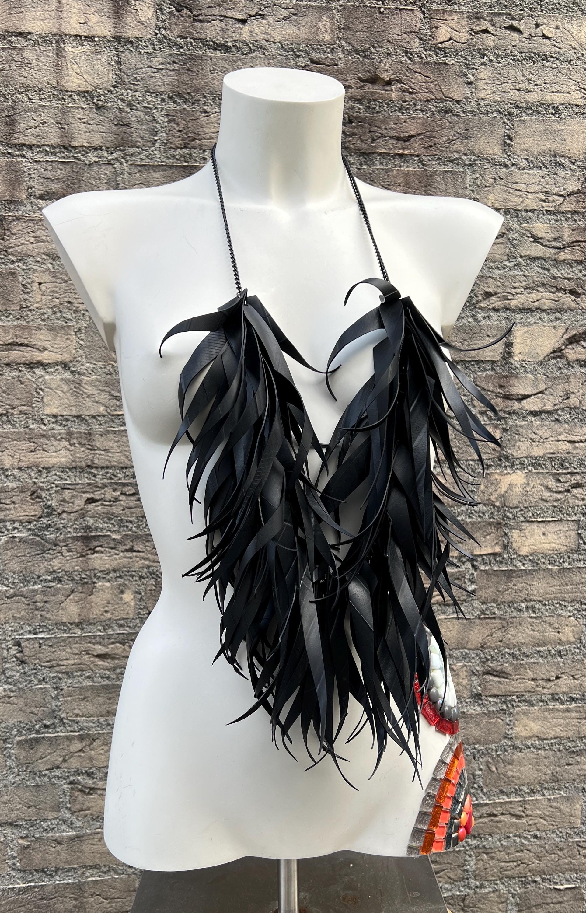 very large, oversized black curly tassel made from upcycled bicycle inner tube tassels on a white mannequin