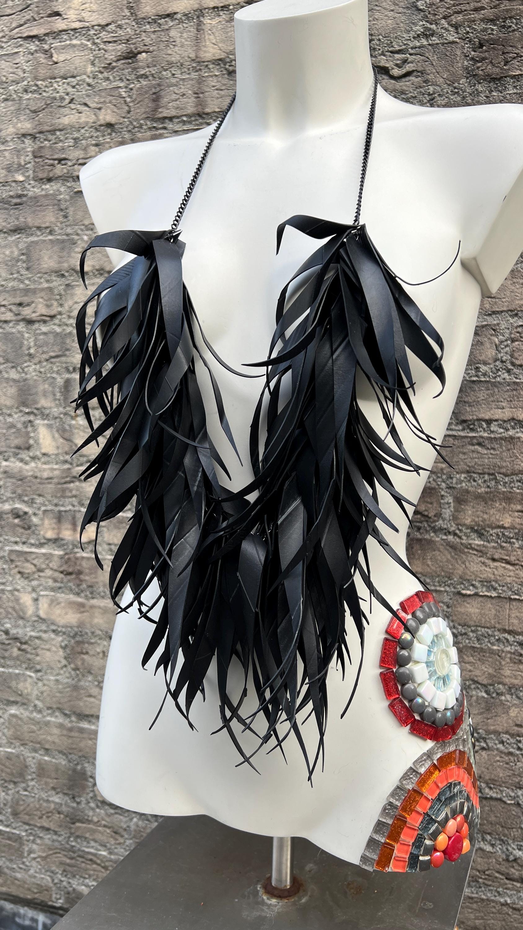 very large, oversized black curly tassel made from upcycled bicycle inner tube tassels on a white mannequin
