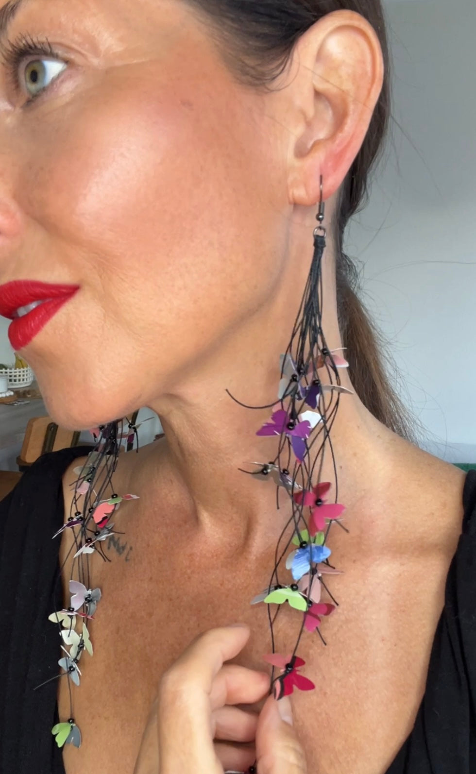Close-up of a woman wearing colorful butterfly earrings made from craft beer and soda cans 