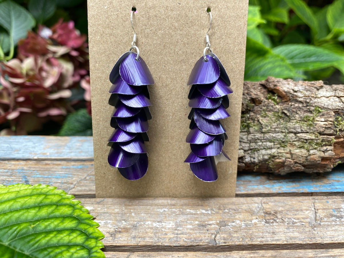 Purple cascade earrings made from upcycled nespresso capsules on a wooden surface with greenery in the background