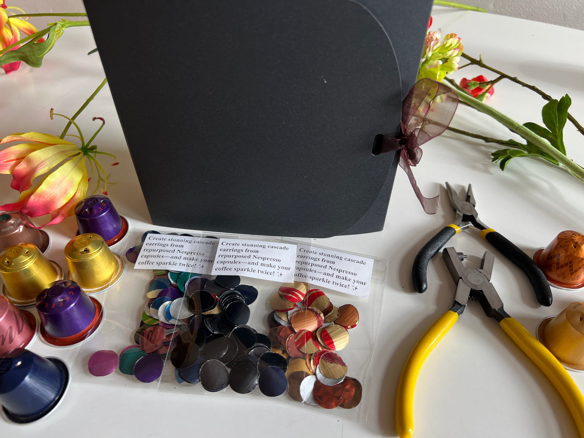laura zabo beginner upcycling craft kit with aluminium circles cut from nespresso and coffee pods, craft pliers, black gift box, and some colourful nespresso capsules 