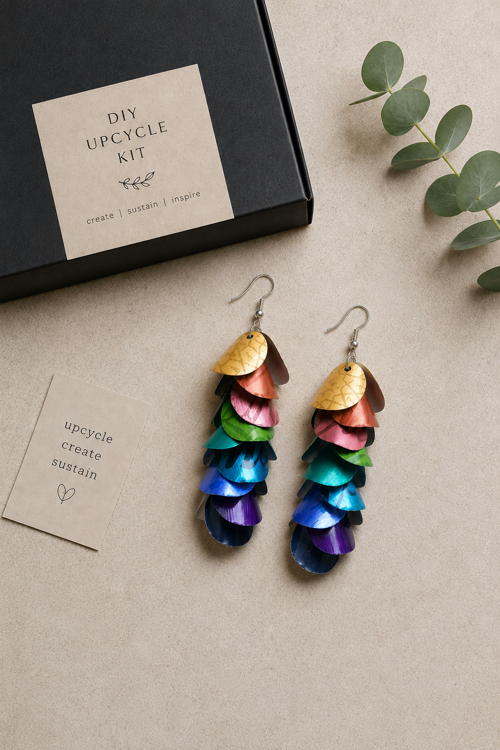 Colorful upcycled earrings on a neutral surface with a 'DIY Upcycle Kit' box.